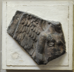 Fragment of a relief slab depicting Victory sacrificing a bull.  Only the lower part of the head and face, the body to below the waist, part of the right arm and right wing remain. 