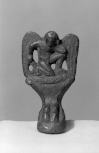 The foot of an Etruscan <i>cista </i>(a box for items of value) in the form of the figure of a winged genius above a claw base. 