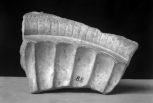 Fragment of the rim and bowl of a large basin, enriched on the interior (from the lip inwards) with the remains of a scale border, convex piped stylised petal fluting and conventional fluting set off by fillet piping at the outer edge. 