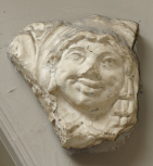 Archaistic male mask-head, part of a panel or border of scroll ornament(?)