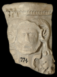 Corner of a Roman funerary (cinerary) urn with an ammon head and garland